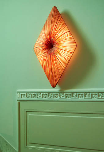 Elegant stairwell featuring a marble staircase, decorative molding, and a striking diamond-shaped orange wall light for a modern, inviting touch